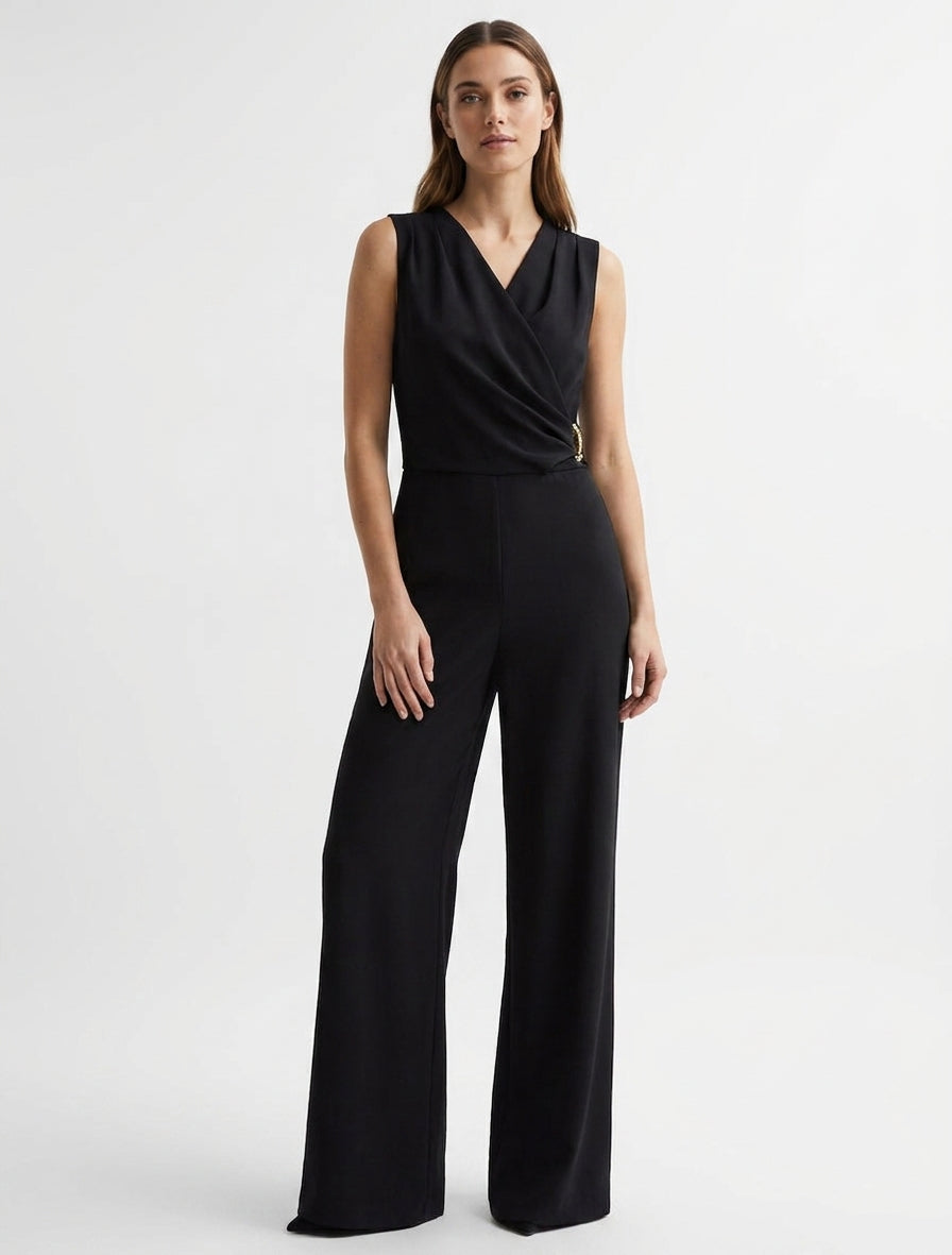 Ruime jumpsuit met overslagkraag, drapeereffect en sieraad. - Zwart